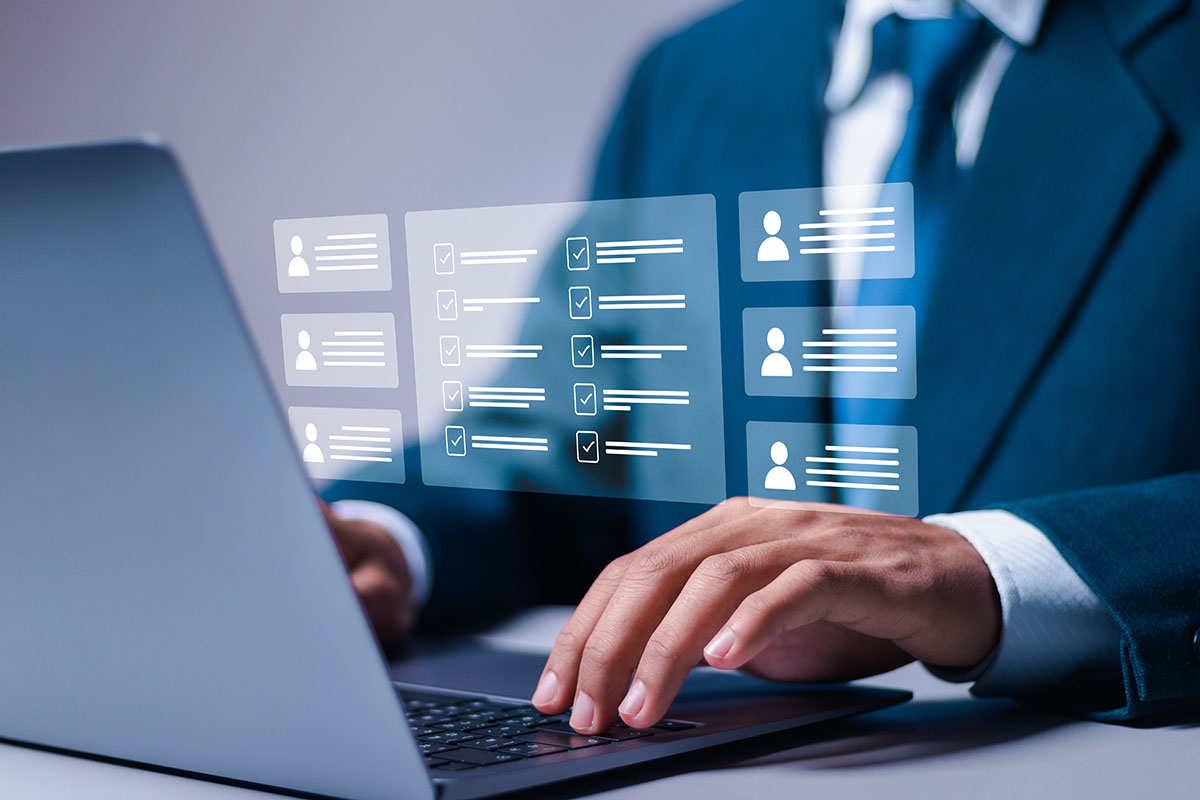 A businessman in a suit typing on a laptop while digital appraisal checklists and employee profile cards float above the keyboard