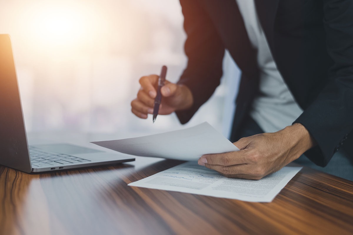 Businessman signing an employment contract at a desk, pen in hand