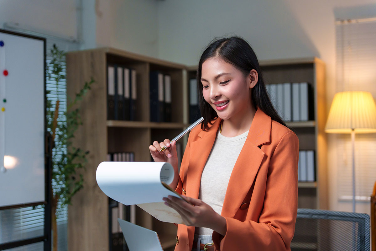Businesswoman reviewing compliance paperwork on a clipboard in a modern office